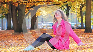 Happy woman with autumn leaf in park, romantic mood