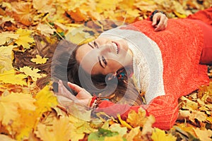 Happy woman autumn portrait, lying in autumn leaves