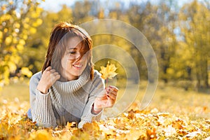 Happy woman in autumn season relax. Brunette girl lying and smiling at autumn