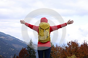 Happy woman with backpack admiring mountain landscape, back view. Feeling freedom