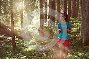 Happy woman with backpack walking on hiking trail path in forest woods during sunny day.Group of friends people summer