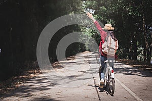 Happy woman backpacker with white bicycle in nature