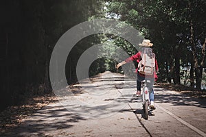 Happy woman backpacker with white bicycle in nature