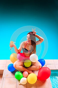 Happy woman with balloons and cocktail at poolside