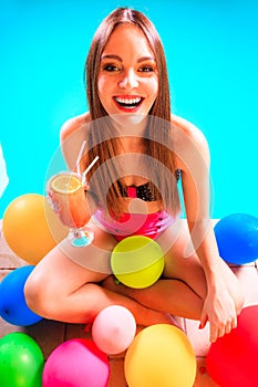 Happy woman with balloons and cocktail at poolside