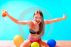 Happy woman with balloons and cocktail at poolside