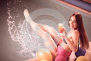 Happy woman with balloons and cocktail at poolside