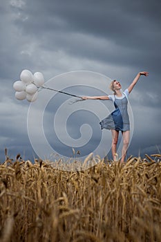 Happy Woman with Balls in the Field on the Thunderstorm Sky