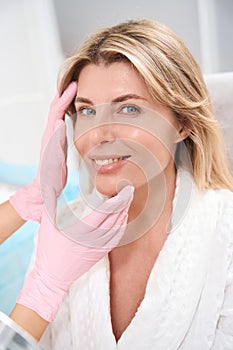 Happy woman in a bathrobe at an appointment with esthetician