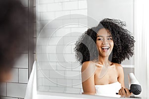 Happy woman in bathroom drying her curly hair