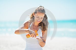 Happy woman on beach applying sun screen creme