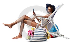 Happy woman at the beach on deck chair, sunbathing, uses the mobile phone, isolated in the white background, concept a summer