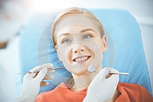 Happy woman is being examined by dentist at dental clinic. Healthy teeth and medicine, stomatology concept