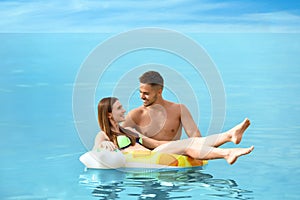 Happy woman in bikini floating on inflatable ring and her boyfriend in sea