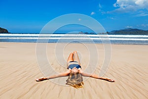 Happy woman in bikini relax, enjoy sunbathing on sand beach