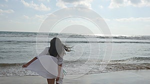 Happy woman in bikini and shirt walking on the beach at the ocean water. Young beautiful girl enjoying life and having