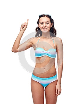 Happy woman in bikini swimsuit pointing finger up