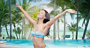 Happy woman in bikini swimsuit with raised hands
