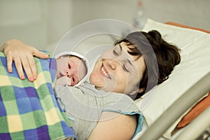 Happy woman after birth with a newborn baby