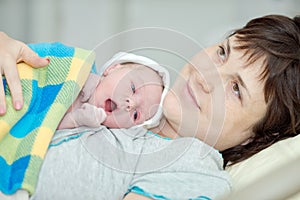 Happy woman after birth with a newborn baby