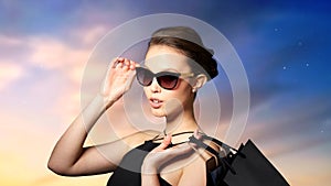 Happy woman in black sunglasses with shopping bags