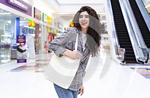 Happy woman with blank eco bag shopping in city mall