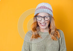 Happy woman blinks one eye, isolated on yellow background. Studio shot of cheerfully blond young girl