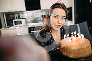 Happy woman blogger filming herself on camera on her birthday, caucasian brunette girl with cake and candles at home