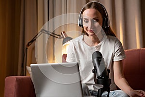 A happy woman, a blogger, recording a broadcast, putting on headphones online, talking into a microphone with an