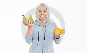 Happy woman with blond hair and beautiful smile holds two oranges, lemon and a pears in her hands for a healthy diet with