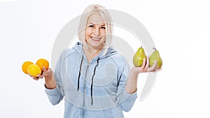 Happy woman with blond hair and beautiful smile holds two oranges, lemon and a pears in her hands for a healthy diet with