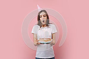 Happy woman blowing out candles on birthday cake