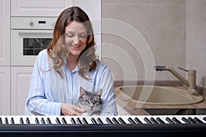 A happy woman in a blue nightie and a funny pet learn to play the piano in their home kitchen