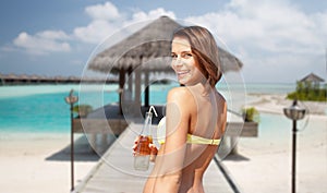Happy woman with bottle of drink on summer beach