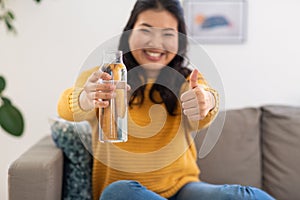 happy woman with bottle of water showing thumbs up