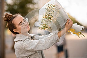 happy woman with bouquet of white small camomile flowers