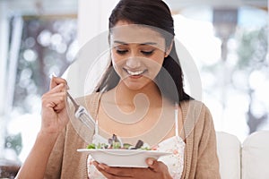 Happy woman, bowl and eating salad for diet, healthy snack or natural nutrition on sofa in living room at home. Female