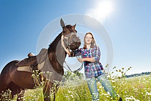Happy woman with brown stallion in countryside