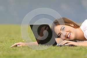 Happy woman browsing internet on a laptop on the grass