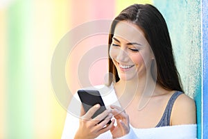 Happy woman is browsing smart phone beside a colorful wall