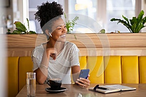 Happy woman in cafe talking on the phone with earphones