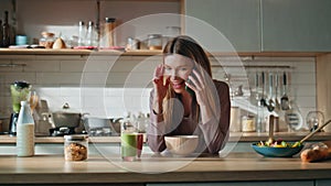 Happy woman calling kitchen countertop. Happy girl talking smartphone at morning