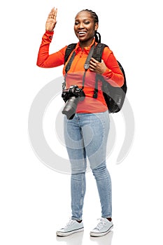 happy woman with camera and backpack waving hand