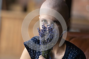Happy woman with cancer holding bunch of flowers at face