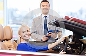 Happy woman with car dealer in auto show or salon