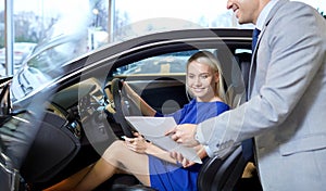 Happy woman with car dealer in auto show or salon