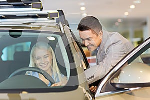 Happy woman with car dealer in auto show or salon