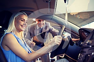 Happy woman with car dealer in auto show or salon