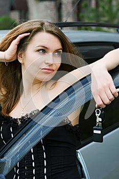 Happy young fashion woman by her car