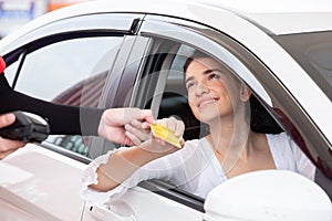 Happy woman in car paying credit card after refuel car â€‹spending instead of cash at gas station. petrol business finance energy